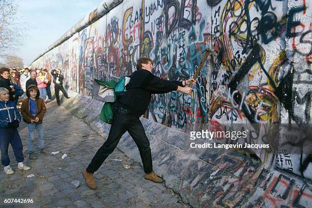 Man welds a pickaxe to participate in the destruction of the Berlin Wall, between the Postdam Platz and the Brandenburg Gate. The Berlin Wall...