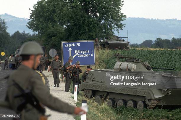 During the civil war in Slovenia, a convoy of the Yugoslavian Federal Army travels in position with T55 and T72 tanks through rural agricultural...