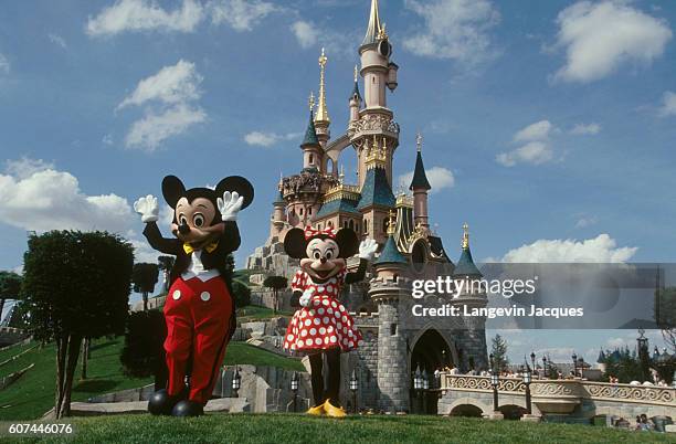 Mickey and Minnie Mouse stand outside Sleeping Beauty Castle at Disneyland Paris.