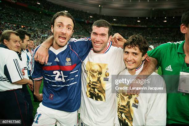 France's players Christophe Dugarry, Zinedine Zidane and Bixente Lizarazu celebrate on the field after their 3-0 victory over Brazil in the final of...