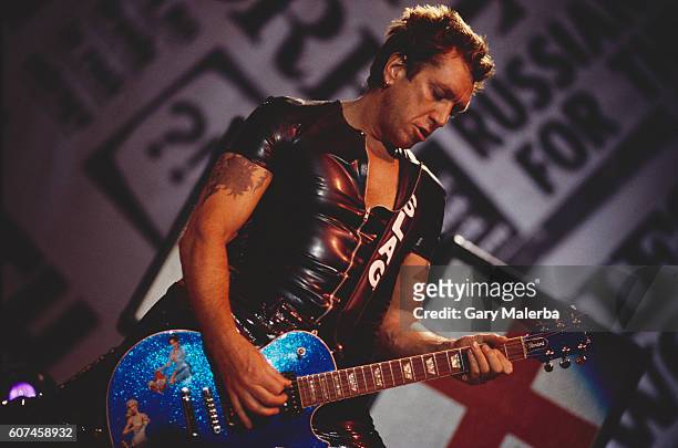 Steve Jones of The Sex Pistols plays his shiny blue electric guitar during a concert, circa 1980.