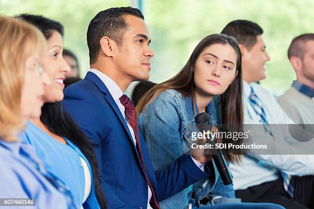 hispanic man asks question during meeting - town hall meeting stock pictures, royalty-free photos & images
