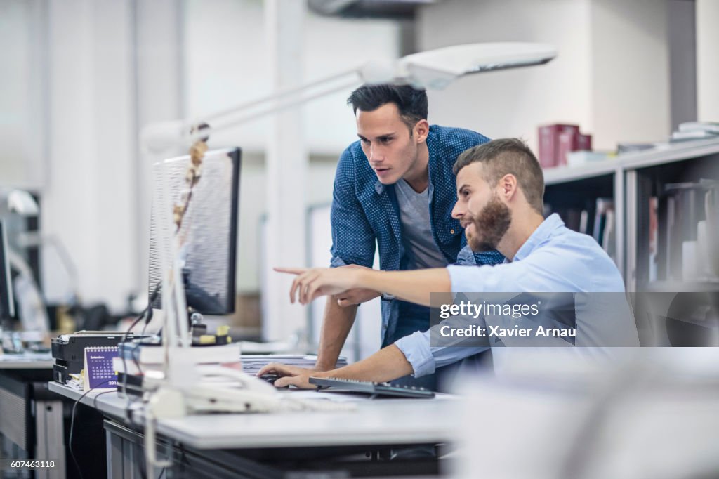 Industrial designers at the office discussing project on the computer