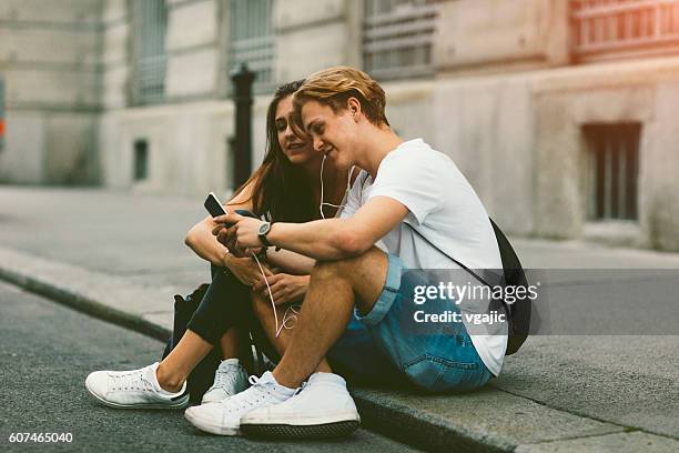 teenage couple mobile gaming outdoors. - boy girl stockfoto's en -beelden