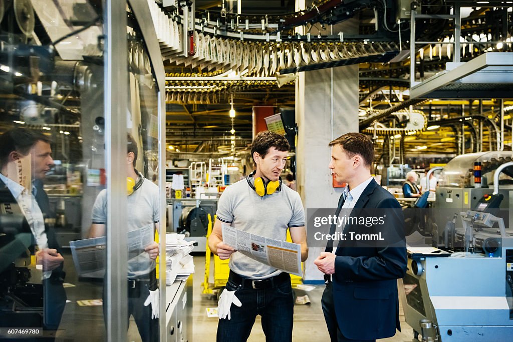 Mechaniker und Manager im Gespräch in riesiger Fabrik