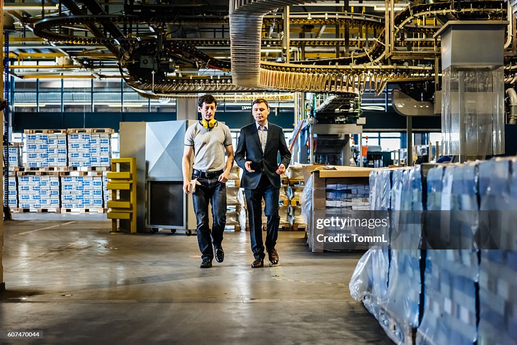 Mechaniker und Manager im Gespräch und Gehen in der Fabrik