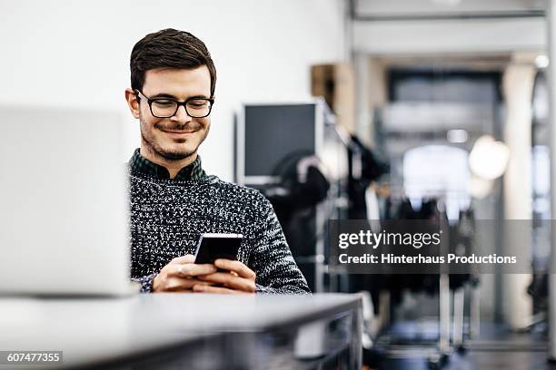 young casual businessman looking at his smartphone - authentic photo office bildbanksfoton och bilder