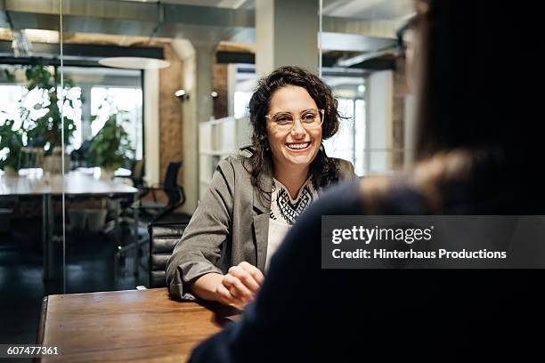 smiling latin businesswoman during a meeting - candid office stock-fotos und bilder