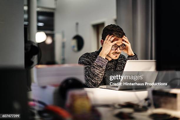 young businessman holding his head and pondering - young adult thinking stock pictures, royalty-free photos & images