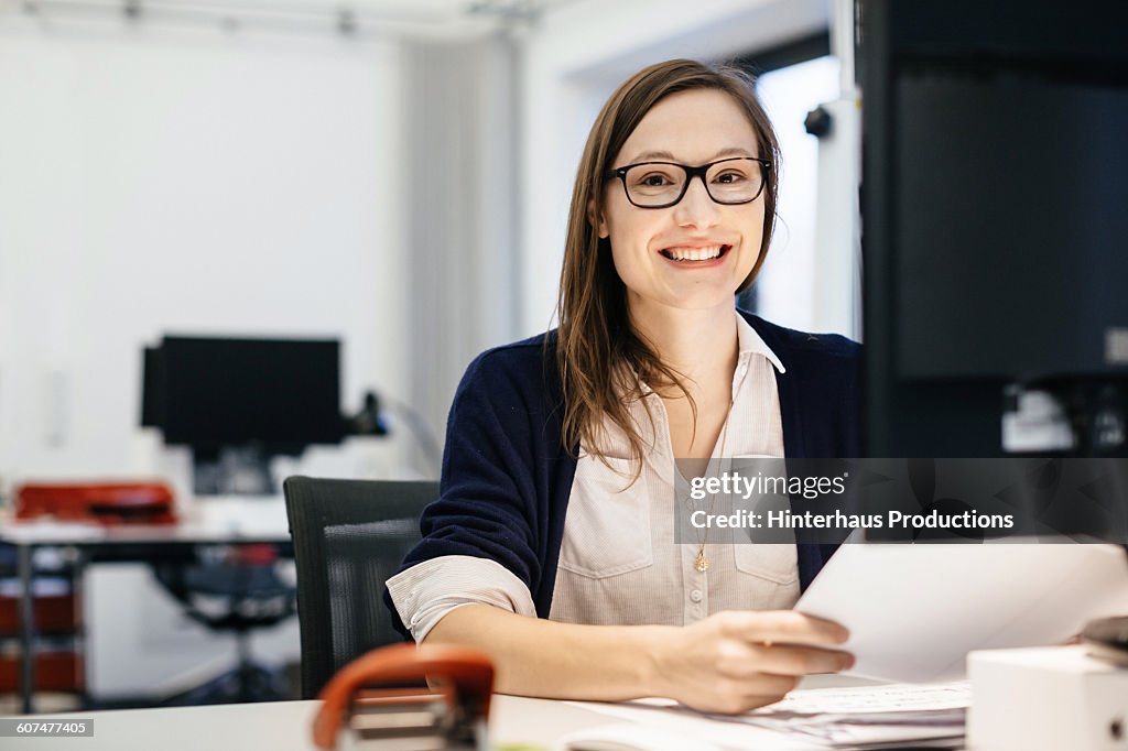Casual busineswoman smiling at a desk in an office