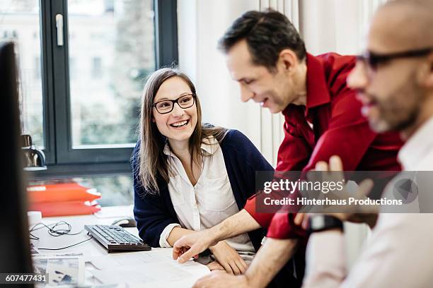 businesswoman smiling at colleague in office - männer gruppe stock-fotos und bilder
