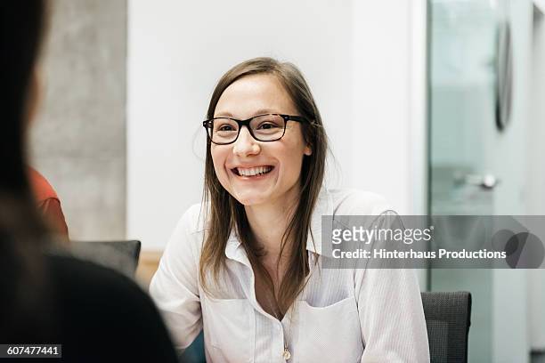 young woman smiling in a business meeting. - offener kragen stock-fotos und bilder