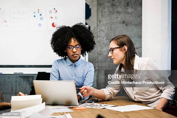 two young women having a discussion in a business - workplace tech 個照片及圖片檔