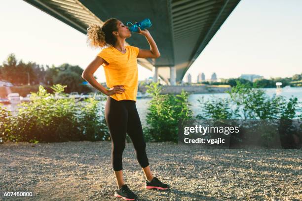 latina runner - woman drinking water from bottle stock-fotos und bilder