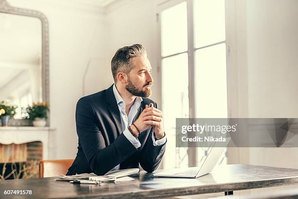 businessman staring out of the window with a pensive expression - staring stock pictures, royalty-free photos & images