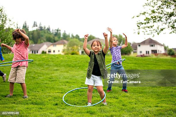group of children hoola-hooping at the nearby park - class hula hoop stockfoto's en -beelden