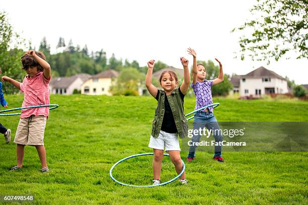 group of children hoola-hooping at the nearby park - hooping stock pictures, royalty-free photos & images