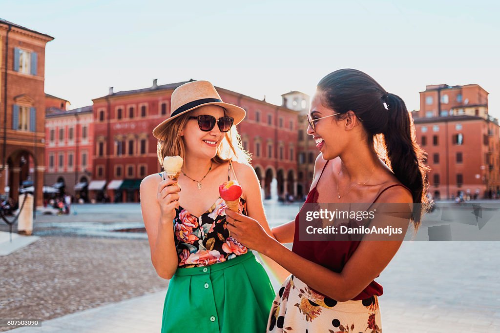 Two cheerful young women eating ice cream and having fun