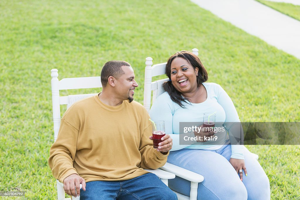 Young black couple sitting, talking, drinking