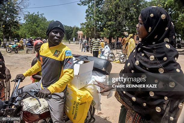 Cameroonian displaced woman is seen loading her donated food on a motorcycle outside a distribution center in Koza, in the extreme northern province,...