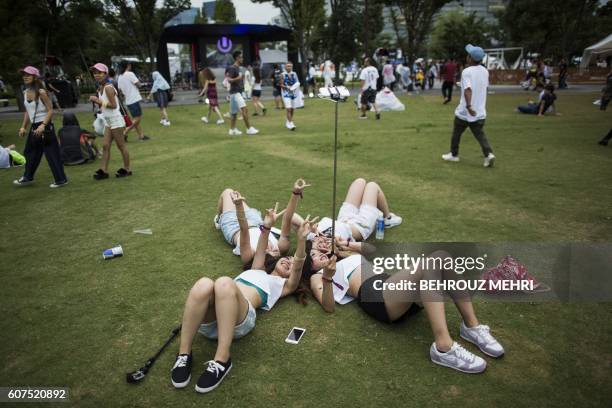 Japanese women take a selfie during the Japan Ultra Music Festival at Odaiba Ultra Park in Tokyo on September 18, 2016.