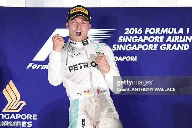 Mercedes AMG Petronas F1 Team's German driver Nico Rosberg punches the air on the podium as he celebrates winning the Formula One Singapore Grand...