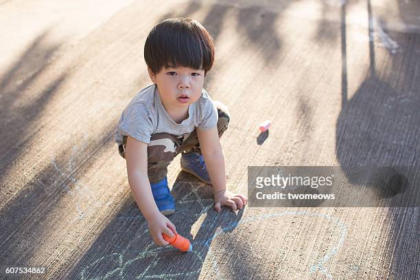 toddler boy drawing on pavement with chalk. - right cerebral hemisphere stock pictures, royalty-free photos & images