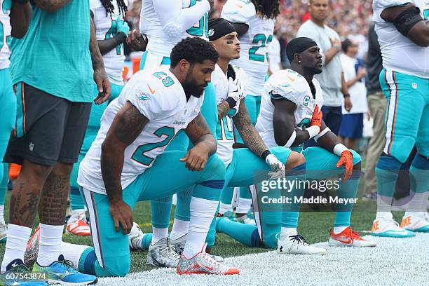 Arian Foster, Kenny Stills and Michael Thomas of the Miami Dolphins kneel during the national anthem before the game against the New England Patriots...