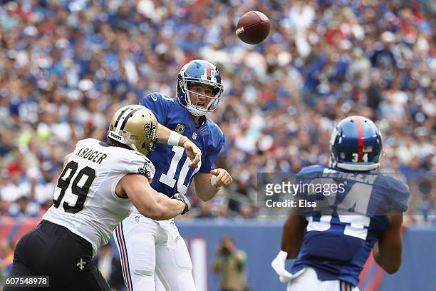 Quarterback Eli Manning of the New York Giants throws a pass to teammate Shane Vereen against Paul Kruger of the New Orleans Saints during the first...