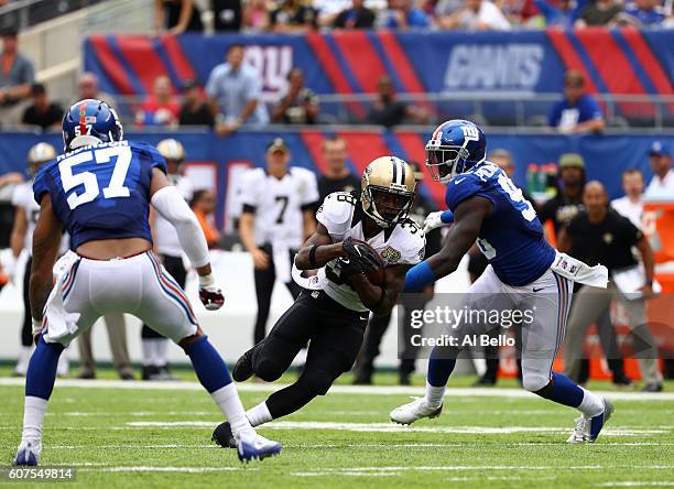 Travaris Cadet of the New Orleans Saints runs the ball against Jason Pierre-Paul of the New York Giants during the first half at MetLife Stadium on...