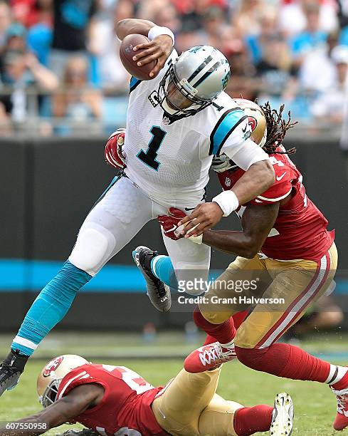 Cam Newton of the Carolina Panthers hurdles Ray-Ray Armstrong and Jimmie Ward of the San Francisco 49ers during the game at Bank of America Stadium...