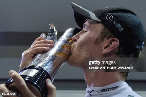 Mercedes AMG Petronas F1 Team's German driver Nico Rosberg kisses the trophy as he celebrates his victory after the Singapore Grand Prix night race...