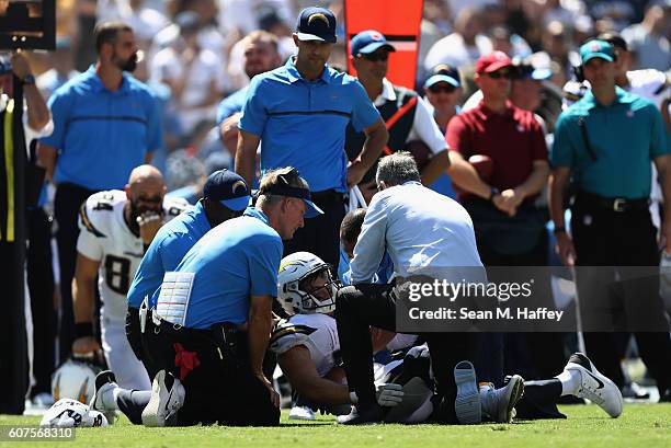 An injured Danny Woodhead of the San Diego Chargers is on the field surrounded by medical and coaching staff including head coach Mike McCoy in the...