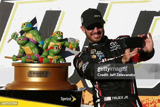 Martin Truex Jr, driver of the Furniture Row/Denver Mattress Toyota, poses with the trophy in Victory Lane after winning the NASCAR Sprint Cup Series...