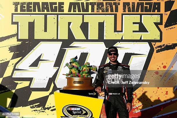 Martin Truex Jr, driver of the Furniture Row/Denver Mattress Toyota, poses with the trophy in Victory Lane after winning the NASCAR Sprint Cup Series...