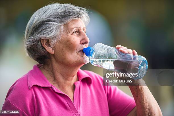 senior woman drinking refreshing water from a bottle. - thirsty stock pictures, royalty-free photos & images