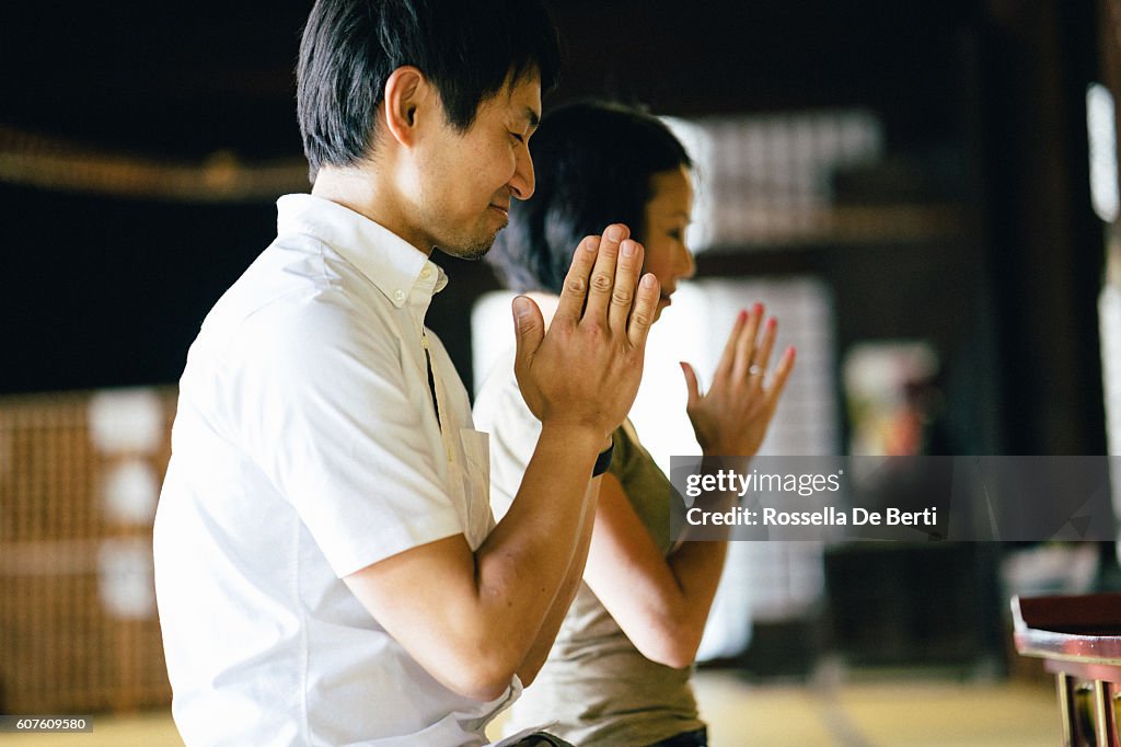 Japanese couple praying in a buddhist temple