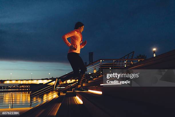 young woman jogging at night near river. - citylight stockfoto's en -beelden