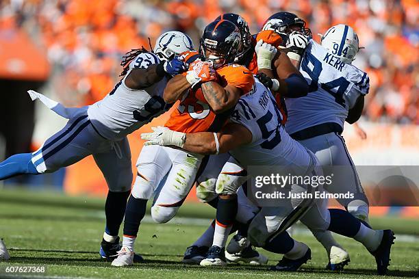 Running back Devontae Booker of the Denver Broncos is tackled by outside linebacker Erik Walden and nose tackle David Parry of the Indianapolis Colts...