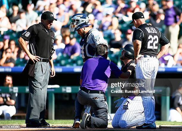 Walt Weiss of the Colorado Rockies and the Rockies trainer check on Mark Reynolds following a hit by pitch in the bottom of the fifth inning of a...