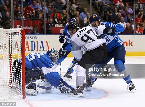 Connor McDavid of Team North America tries to push the puck past Pekka Rinne with pressure from Ville Pokka of Team Finland during the World Cup of...