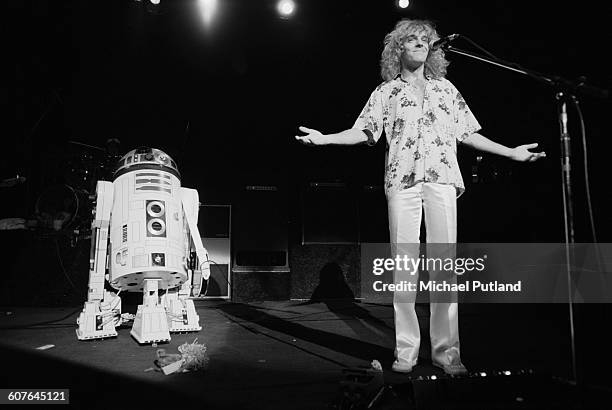 English singer and guitarist Peter Frampton appears bemused after the droid, R2-D2 from the film 'Star Wars', brought Frampton's guitar on stage for...
