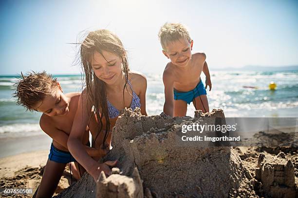 kids  building a sandcastle on beautiful beach - zandkasteel stockfoto's en -beelden