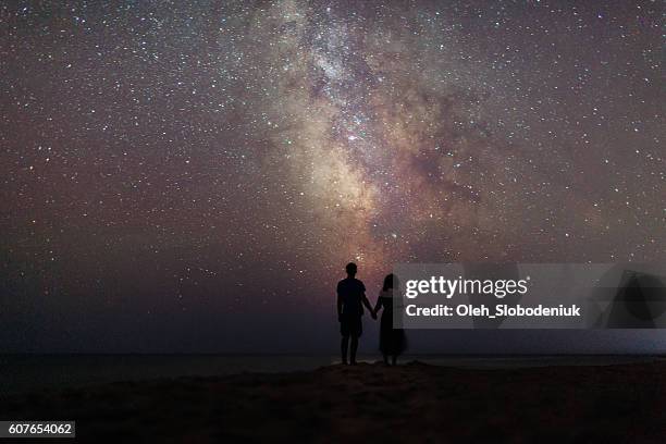 couple near the sea under the starry sky - couple beach sunset stock pictures, royalty-free photos & images