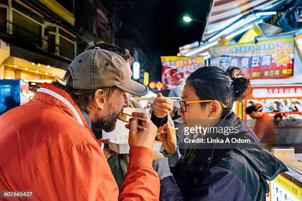 friends eating with chopsticks asian night market - straatvoedsel stockfoto's en -beelden