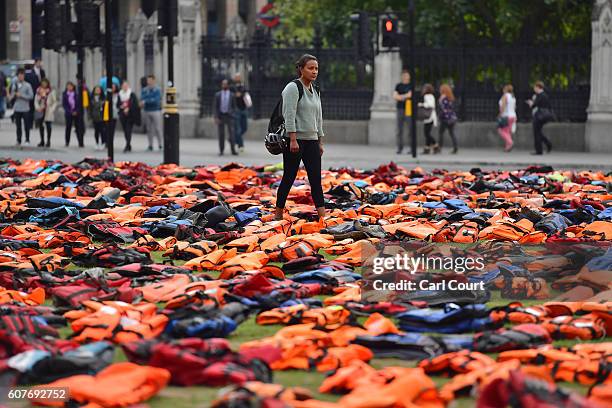 Woman views lifejackets that have been used by refugees to cross the sea to Europe as they are laid out in Parliament Square on September 19, 2016 in...