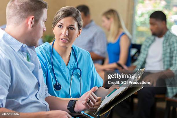 friendly nurse examining patient in hospital triage center, - triage stock pictures, royalty-free photos & images