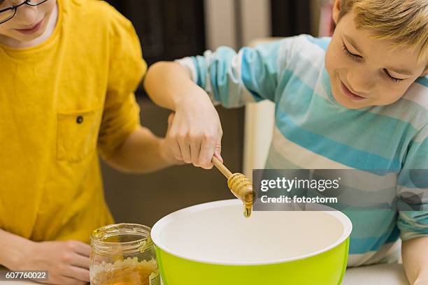 children pouring honey into bowl, bakinng cookies - mixing bowl stock pictures, royalty-free photos & images