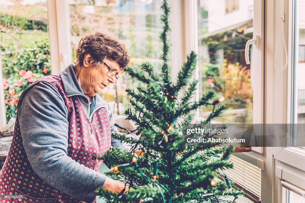 Senior Woman Preparing Christmas Tree on Balcony, Slovenia, Europe