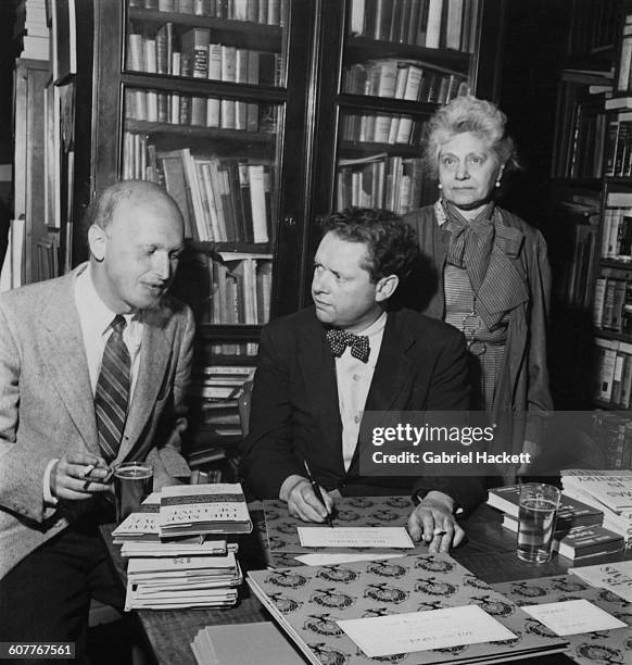 Welsh poet and writer Dylan Thomas signing one of his books for American poet and literary critic John Malcolm Brinnin , during a reception held in...